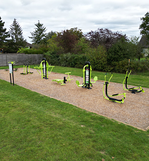 6 machines de fitness de plein air sur un sol en copeaux de bois.