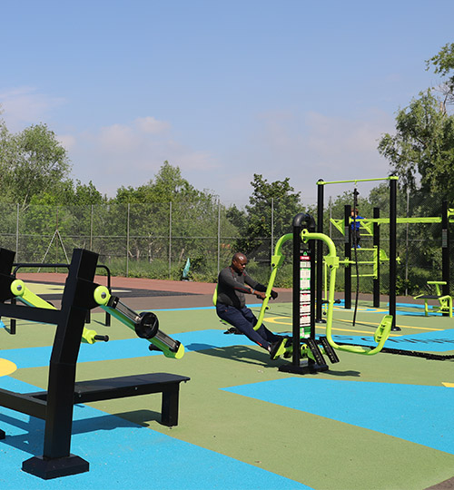 homme en train de faire des squats sur un appareil de sport en plein air.