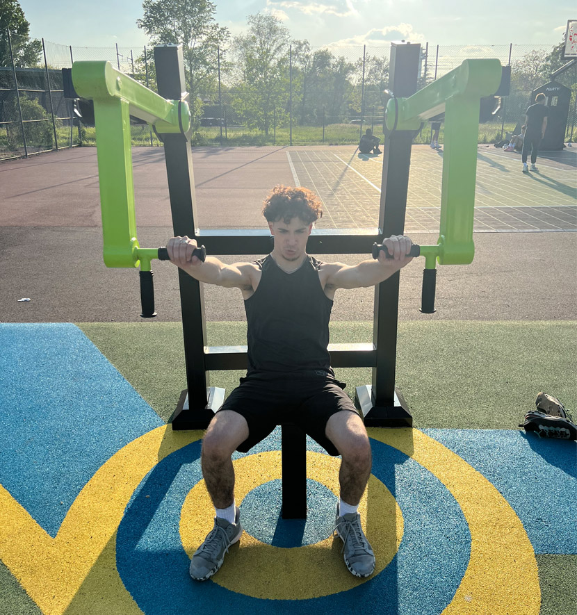 jeune homme en train de pousser sur une machine de sport en plein air.