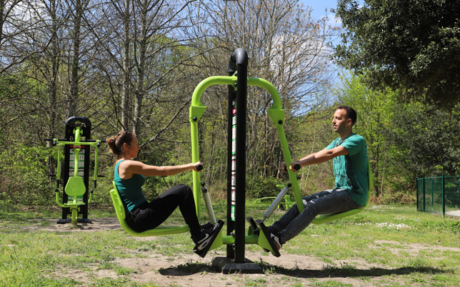 un couple sur une machine de fitness dans un parc.