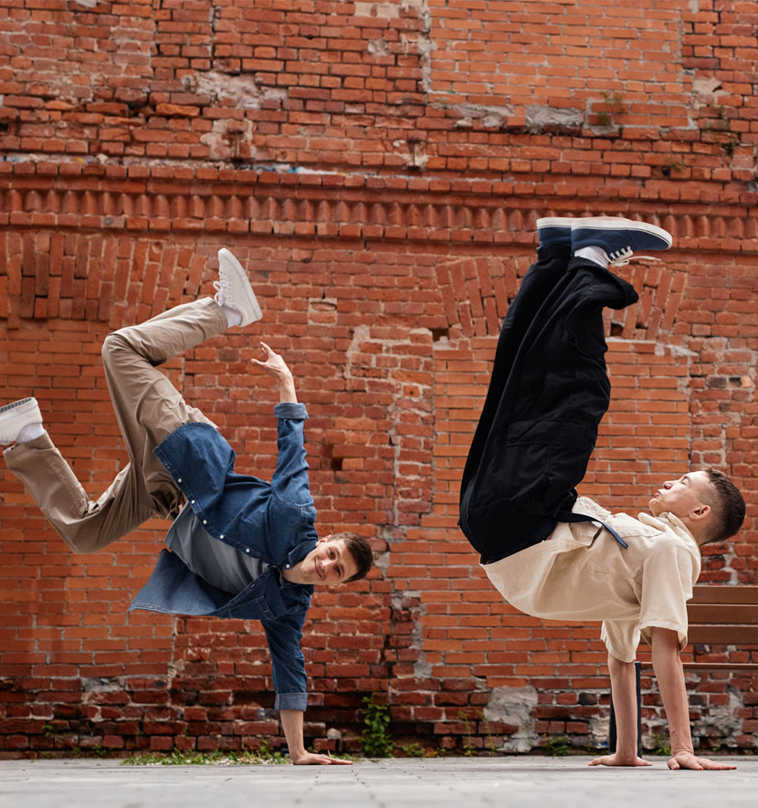 deux danseurs de hiphop devant un mur en brique.