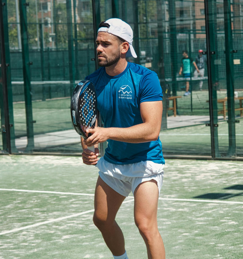 joueur de padel concentré sur un court extérieur.