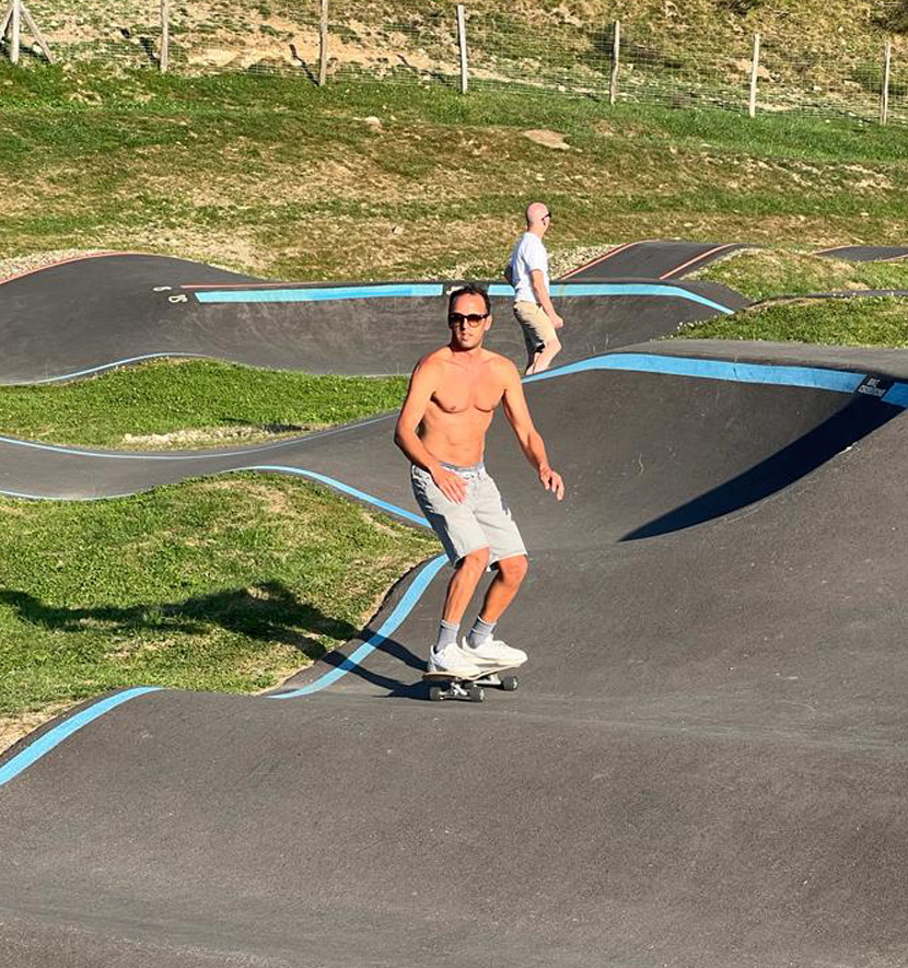 homme torse nu sur un skateboard faisant du pumptrack.