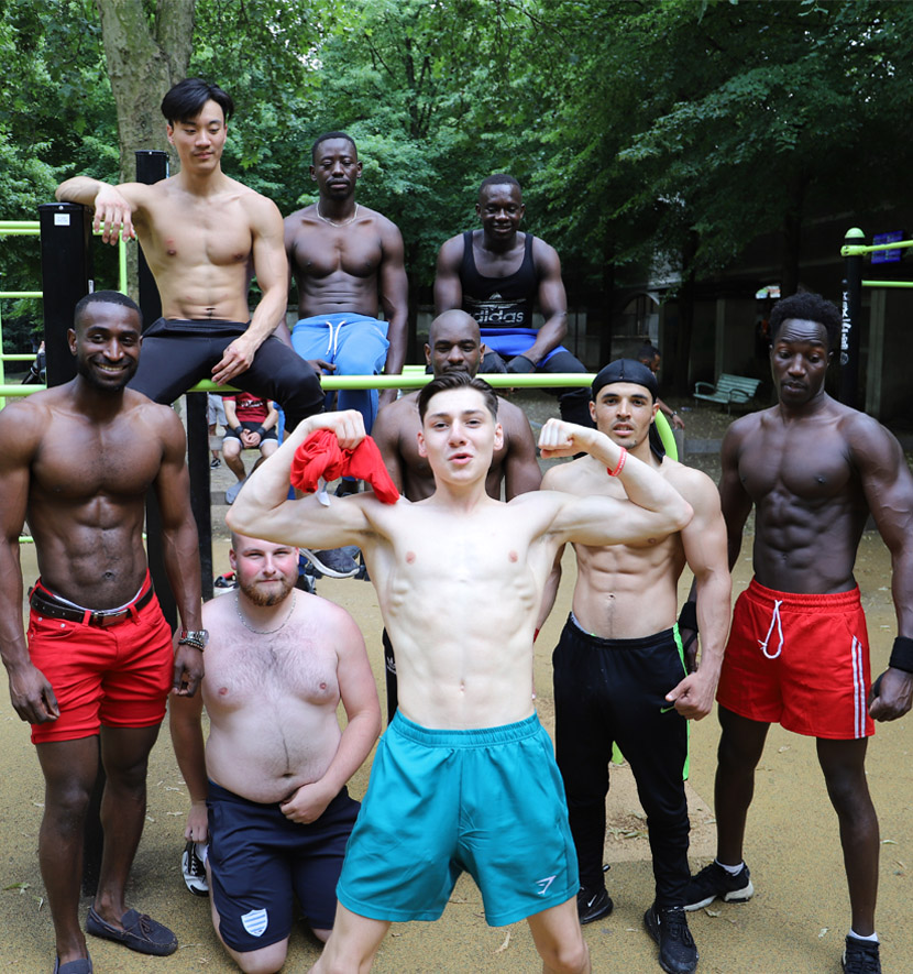 groupe d'hommes musclés posent devant une structure de streetworkout.