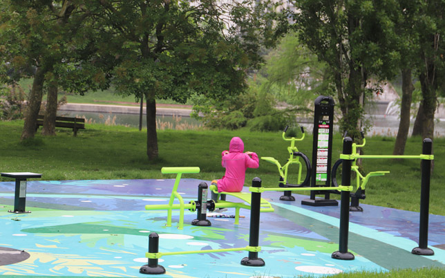 une femme avec une capuche fait du sport sous la pluie sur un terrain de fitness outdoor.