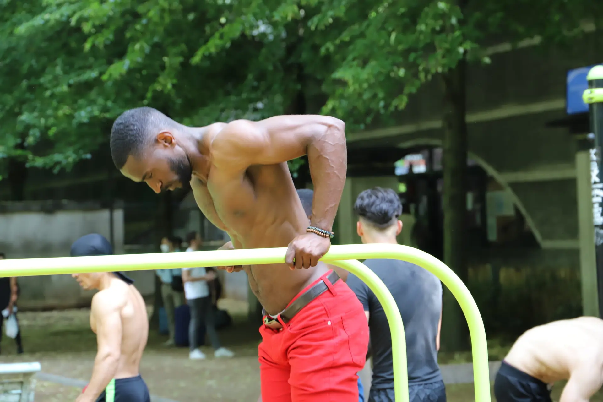 jeune homme faisant des dips sur une barre parallèle dans un parc.