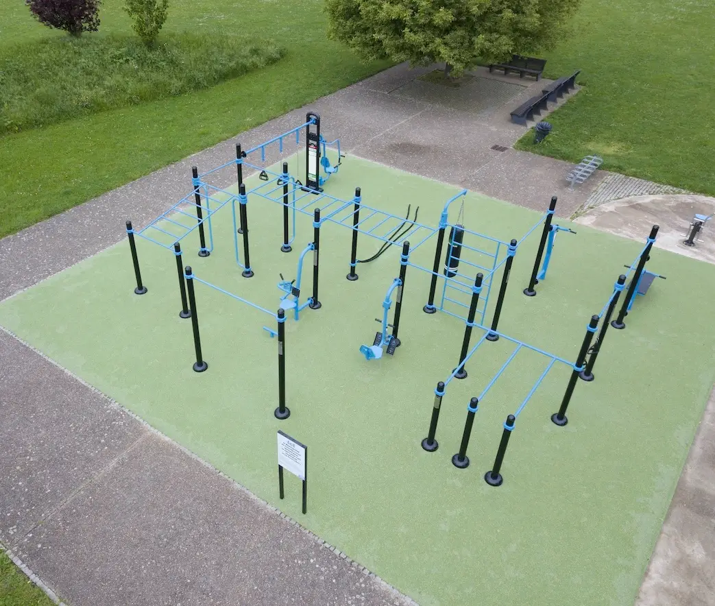 station de streetworkout sur un sol amortissant vert dans un parc.