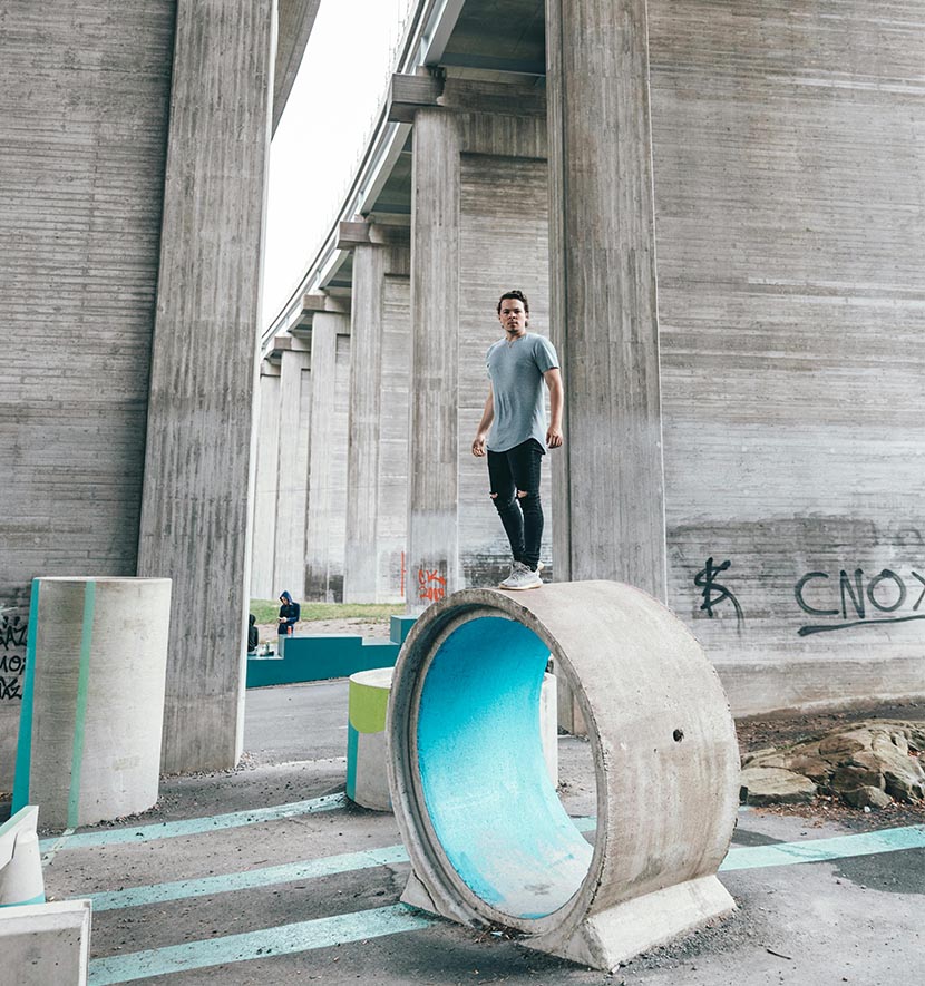 pratiquant de parkour debout sur une structure de béton cylindrique.